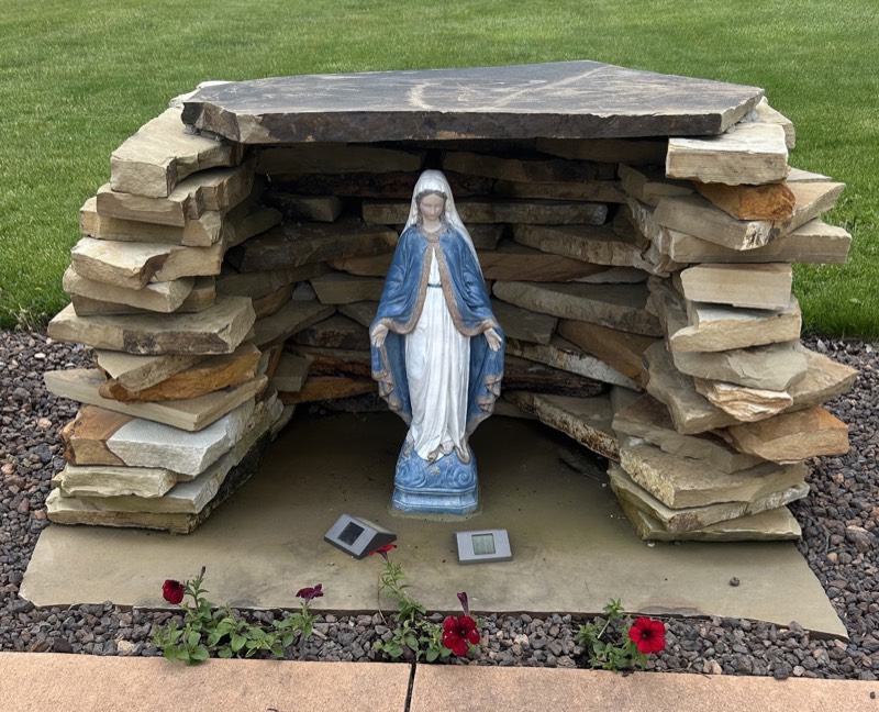 Stacked flagstone grotto sheltering a blue and white Mary statue